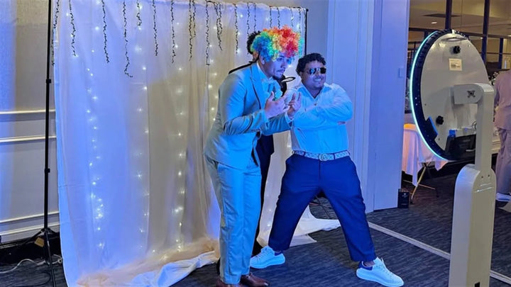 Two guests posing at an event photo booth setup, illustrating how to choose a target market for a photo booth business.