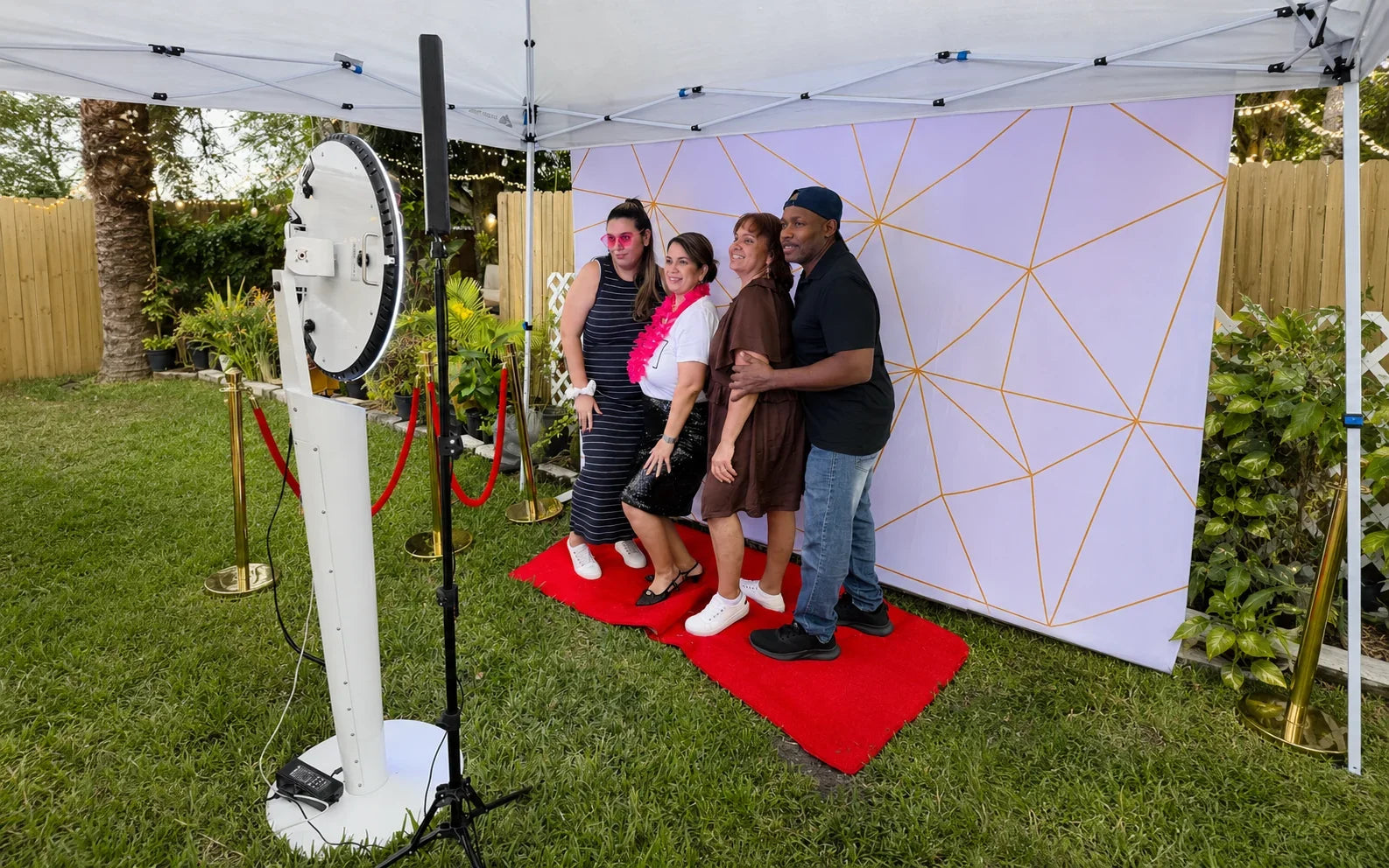 Guests posing at an outdoor 360 photo booth setup under a canopy