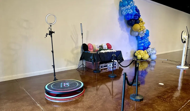 360 photo booth rental setup with ring light, props, queue barriers, and balloon backdrop at an event venue