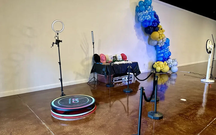 360 photo booth rental setup with ring light, props, queue barriers, and balloon backdrop at an event venue