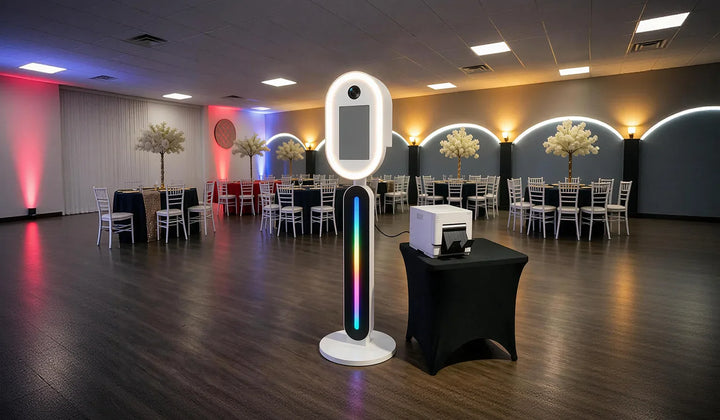 DSLR photo booth setup with camera, touchscreen, LED stand, and printer at an event venue