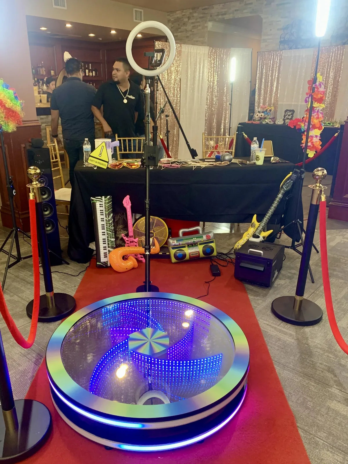Spin Vortex glass 360 photo booth at a real Smart 360 customer party setup with props and a red carpet.
