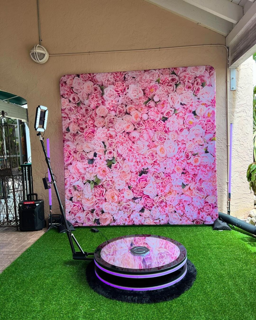 Spin Vortex glass 360 photo booth set up with a pink flower wall.